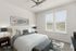 Elegant bedroom featuring a plush bed, contemporary artwork, and two large windows with ample natural light.