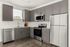 Contemporary kitchen with stainless steel appliances, grey cabinets, and wood flooring, offering a stylish and functional space.