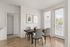 Contemporary dining space with a wooden table, four chairs, and large windows providing natural light.