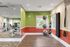 Modern fitness room with vibrant colors, featuring a variety of exercise equipment, wall mirrors, and large windows for natural light.