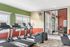 Bright fitness room with modern treadmills, elliptical machines, and a stationary bike, featuring large windows and vibrant walls for an energizing workout atmosphere.
