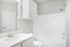 Bright and modern bathroom featuring a sleek white vanity, polished fixtures, and a spacious bathtub for ultimate relaxation.