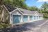 Row of stylish garages with blue doors surrounded by lush greenery.