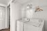 Compact and convenient laundry room with modern washer and dryer, featuring elegant shelving and wooden hangers for organized living.