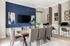 Elegant dining room with blue accent wall, modern artwork, stylish lighting, and a sleek workspace area.