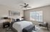 Elegant bedroom with modern decor, featuring a plush bed, sleek lamps, and a cozy seating area. Natural light flows through large windows, creating a serene atmosphere.