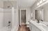 Modern bathroom with elegant white cabinetry, chic countertop, and a relaxing bathtub adjacent to a spacious walk-in closet.