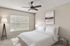 Bright and inviting bedroom featuring a cozy bed with crisp white linens, elegant ceiling fan, and modern floor lamp, creating a serene retreat.