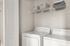 Contemporary laundry room with modern washer and dryer, ample shelving for storage, and neutral decor.