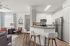 Modern open-concept living space featuring a sleek kitchen with stainless steel appliances, cozy seating area, and elegant bar stools.