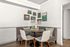 Charming dining nook with a cozy corner bench, stylish round table, and modern chairs, adorned with contemporary art on white walls.