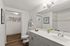 Modern bathroom showcasing sleek gray cabinetry, elegant lighting, and a spacious closet with stylish storage baskets.