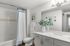 Inviting modern bathroom featuring a sleek vanity, chic lighting, and a stylish shower curtain. Fresh and elegant design with decorative greenery for a serene atmosphere.