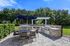 Chic outdoor patio with modern grill and dining area under a stylish pergola, surrounded by lush greenery.