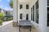 Vibrant outdoor scene with a luxurious apartment complex, featuring a modern ping pong table on a stylish patio near a sparkling pool area and lush greenery.