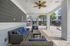 Chic outdoor lounge area with cozy wicker furniture, blue cushions, and stylish ceiling fan, perfect for relaxation and gatherings.