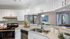 Bright, modern kitchen with sleek white cabinetry, stainless steel appliances, and open view to a cozy living area.