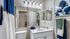 Elegant bathroom with modern fixtures, featuring a large mirror, stylish blue and white decor, and ample counter space with decorative jars.