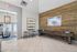 Chic and welcoming apartment lobby with modern decor, featuring a rustic wood accent wall, elegant chandeliers, and stylish wall art. Includes a long wooden bench and a round glass table by the entrance.