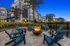 Outdoor fire pit with blue wooden chairs surrounding it in the nighttime with apartments in the background