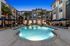 Lit outdoor pool in the nighttime with pool side chairs and large umbrellas