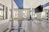Open floor indoor fitness area with mirrors on one wall and windows