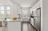Furnished kitchen with large counter, sink, white cabinets, and stainless steel appliances