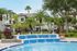 Stunning apartment complex with lush greenery and a sparkling blue pool in the foreground.