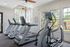 Well-lit apartment fitness room with modern treadmills and an elliptical machine.