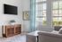 Contemporary living room featuring a stylish gray sofa, wooden console, and artwork bathed in natural light.