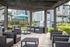 Inviting patio area with modern wicker seating under a wooden pergola, complemented by a barbecue station and lush greenery.
