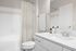 Modern bathroom with white cabinetry, sleek countertop, and shower with a patterned curtain.