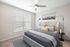 Elegant bedroom with a tufted headboard, plush bedding, modern lamps, and a large window with blinds.