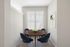 Bright dining nook with a round wooden table and modern blue chairs.