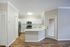 Modern kitchen with sleek white cabinetry, stainless steel appliances, and a spacious quartz countertop, beautifully illuminated by natural light.
