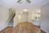 Bright open-concept living space with modern kitchen, elegant wood floors, and cozy carpeted stairway.