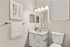 Elegant bathroom with modern fixtures, featuring a sleek white vanity, contemporary lighting, and artistic wall decor.