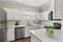 Modern kitchen with sleek white cabinets, stainless steel appliances, and elegant countertop featuring a bowl of fresh green apples.