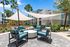Chic outdoor patio area with modern seating and stylish shade sails, surrounded by lush greenery and palm trees, offering a relaxing retreat.