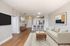 Modern open-concept living area with elegant decor, featuring a stylish kitchen with island seating, cozy sofa, and chic wooden flooring.