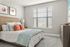 Bright and inviting bedroom with a stylish bed, plush pillows, and soft natural light filtering through window blinds, creating a cozy and welcoming atmosphere.