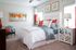Bright and inviting bedroom featuring a plush white and grey bed with vibrant orange accents, modern artwork, and stylish decor.
