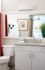 Contemporary bathroom with sleek white cabinetry, modern fixtures, and a large mirror reflecting stylish decor accents.