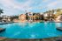 Charming residential property with a crystal-clear pool, modern architecture, and inviting outdoor seating area under a sunny sky.