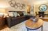 Chic living room with a plush leather sofa, stylish wall art, and elegant dining area, perfect for modern comfort.