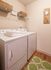 Chic and functional laundry room with modern washer and dryer, cozy green rug, and stylish wall clock.