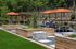 Serene outdoor space with modern seating area, lush greenery, and vibrant orange umbrellas for relaxation and social gatherings.