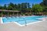 Inviting outdoor pool area with sun loungers, vibrant umbrellas, and lush greenery, perfect for relaxation and leisure.