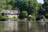 Charming lakeside residence surrounded by lush greenery, featuring elegant fountains and a serene gazebo for peaceful living.