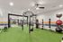 Modern and spacious fitness center with state-of-the-art equipment, lush green flooring, and vibrant accents, perfect for an energizing workout experience.